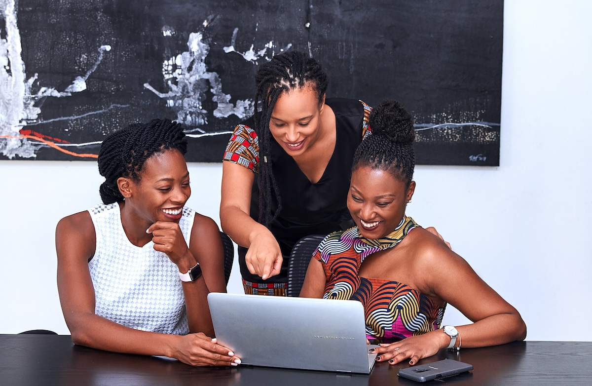 Three black women looking happy while looking at a laptop screen