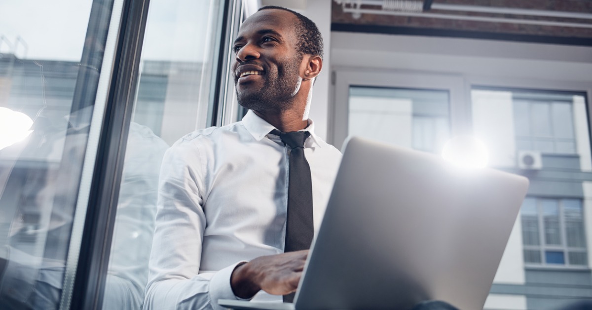 Business man on a laptop looking introspectively out of a window