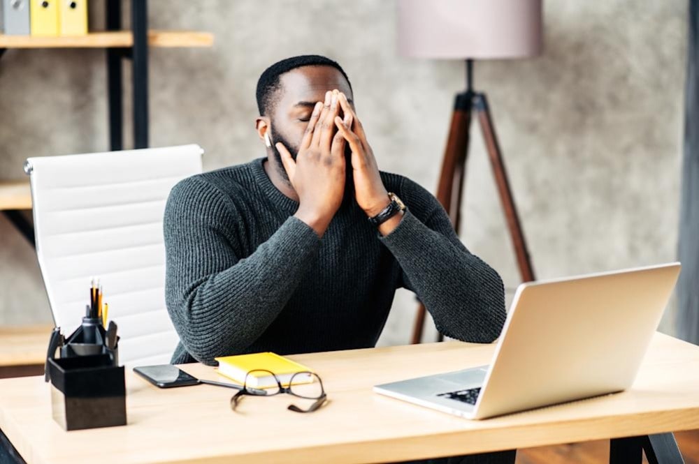 Frustrated man at a desk with his face in his hands