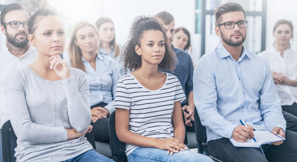 An audience with three people sitting in the foreground