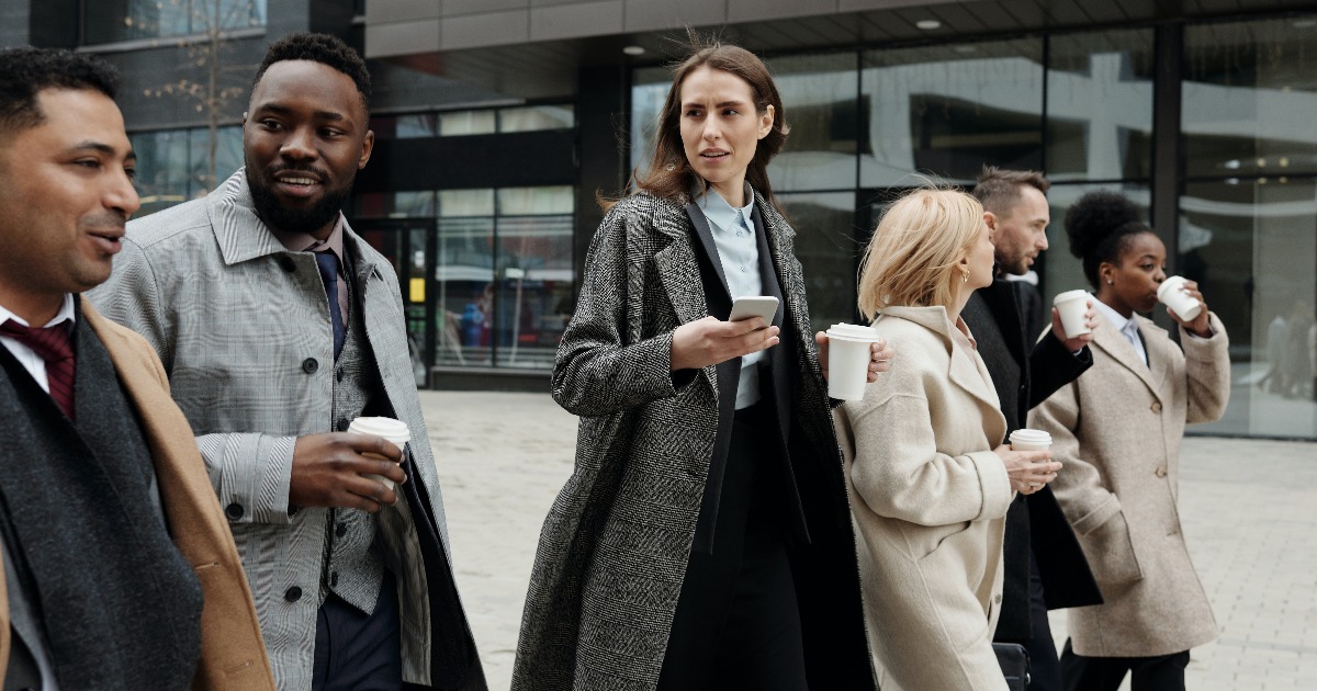 Business people walking side-by-side while holding coffee and talking