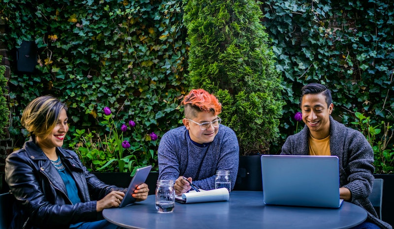 Three smiling people at a table having a meeting