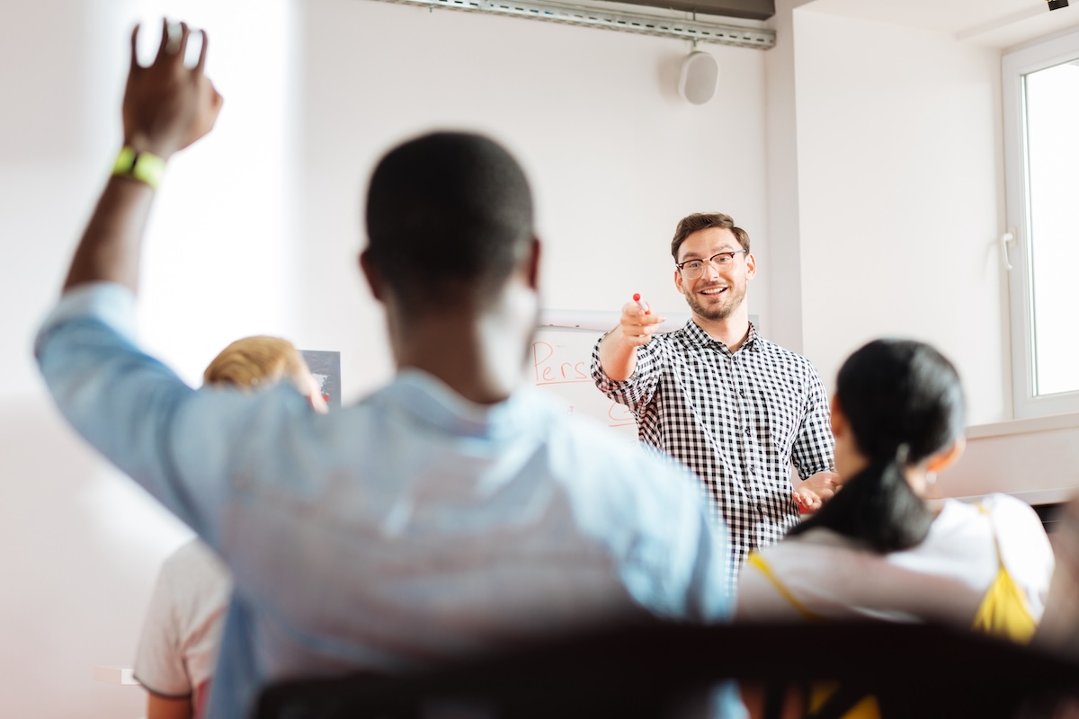 Teacher pointing at a student with his hand up in a training class