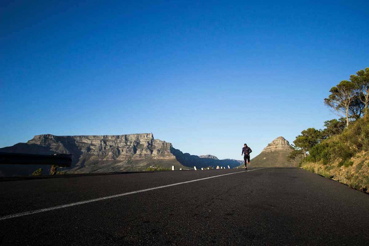 A runner on the road with Table Mountain and Lion's Head