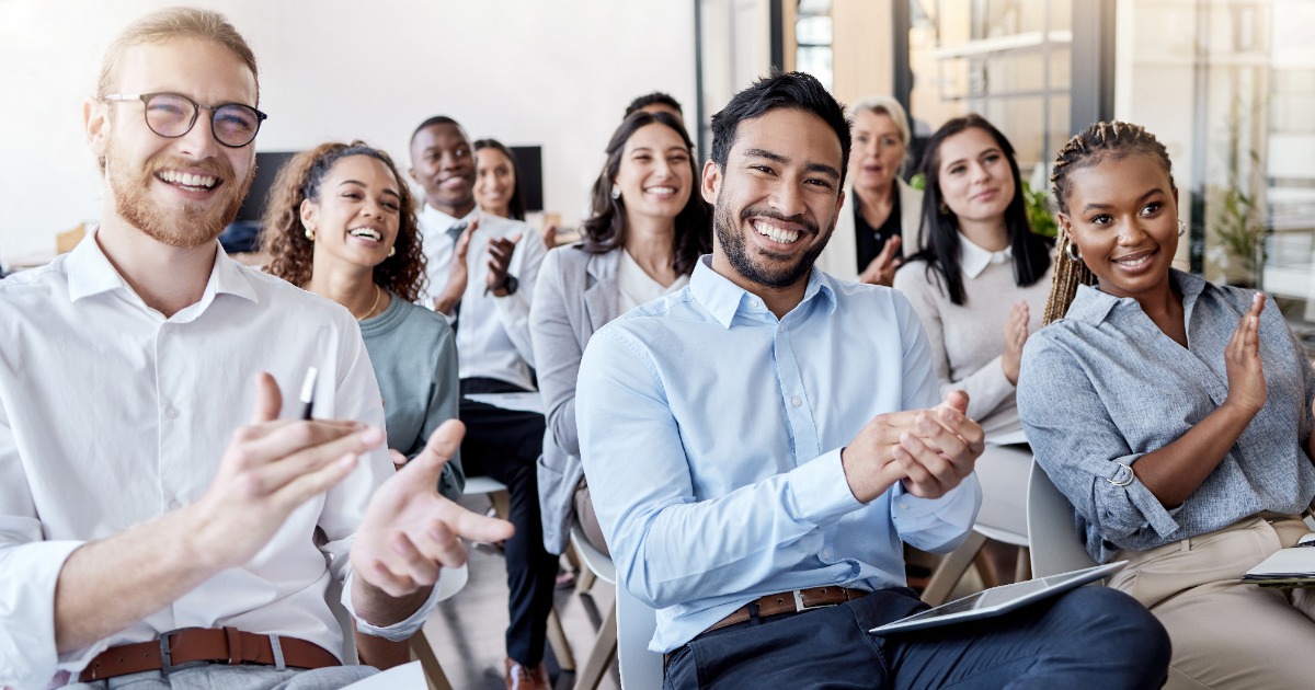 An audience of young people smiling and clapping their hands