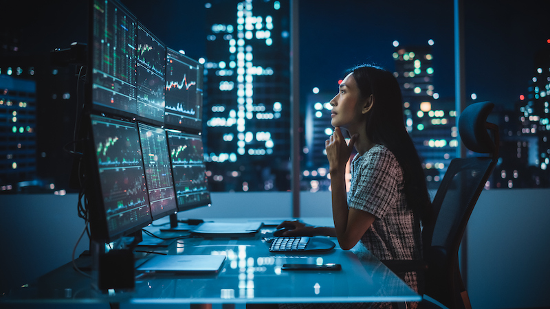 Woman sitting at a desk looking at multiple computer screens