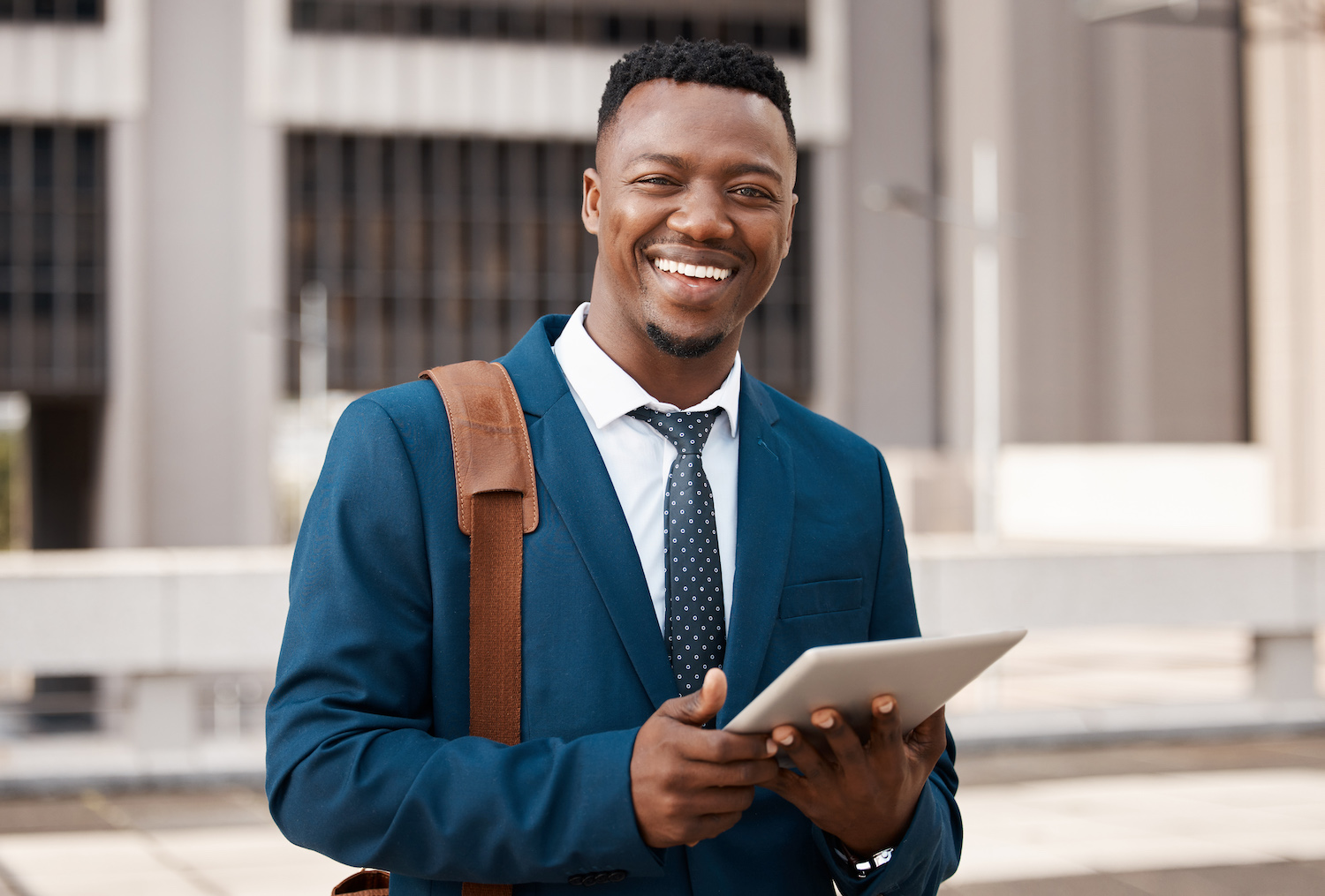 Smiling black man in suit with a tablet in his hands