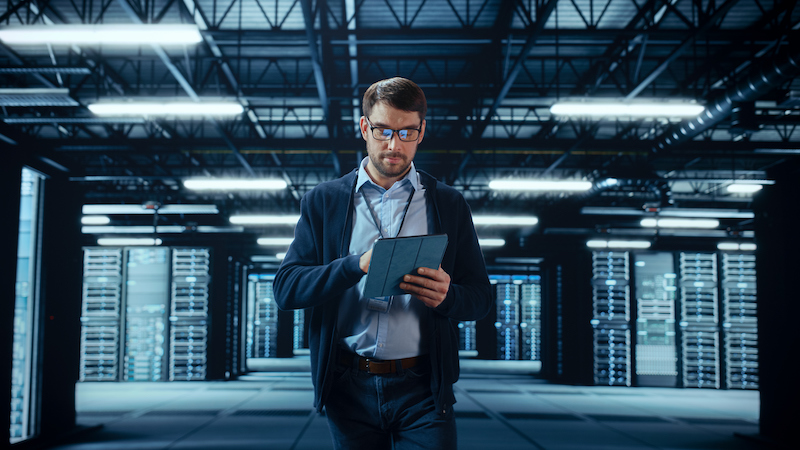 Technician walking through a server room while looking at a tablet