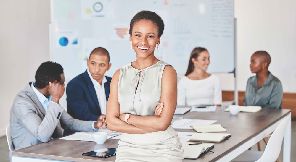 Young woman smiling at the camera in a boardroom with colleagues in the background