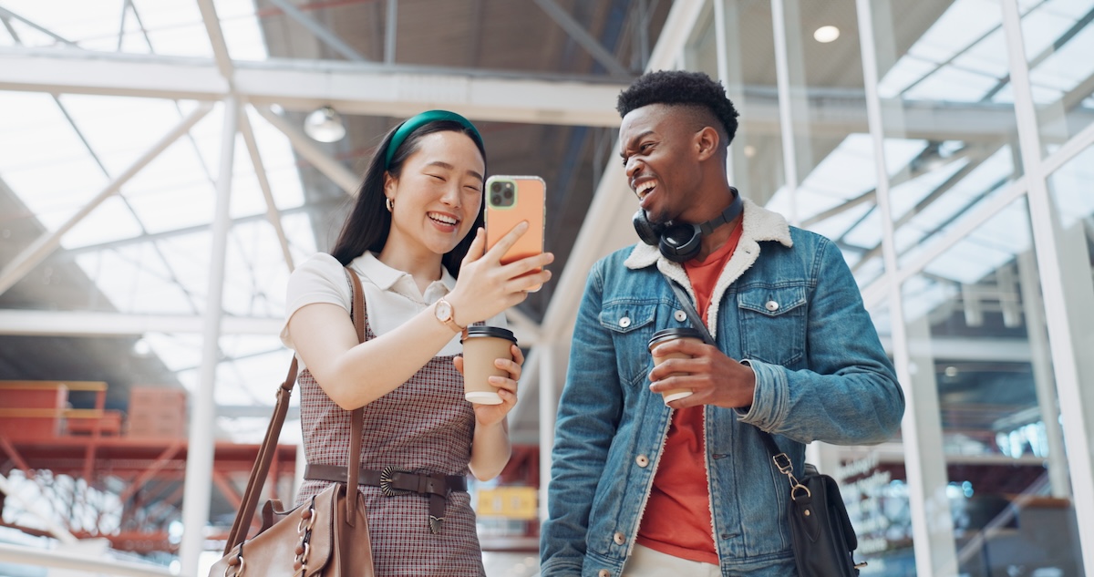 Two young people smiling in a shopping while looking at a phone